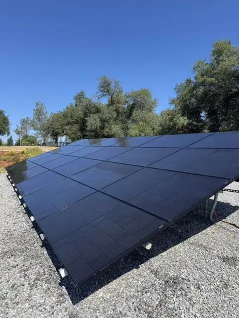 The same ground-mounted panels after cleaning, deep black under a blue sky