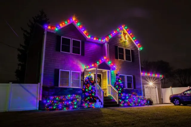 A two-story home with multicolor bulbs along the rooflines