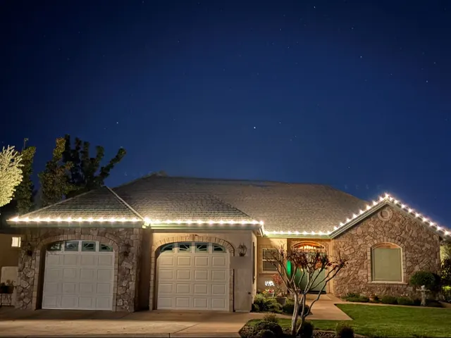 A stone-front home at dusk with one warm white line along the eaves